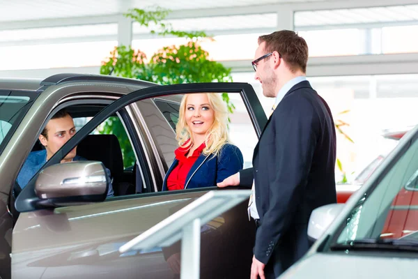 Pareja comprando coche nuevo en el concesionario — Foto de Stock