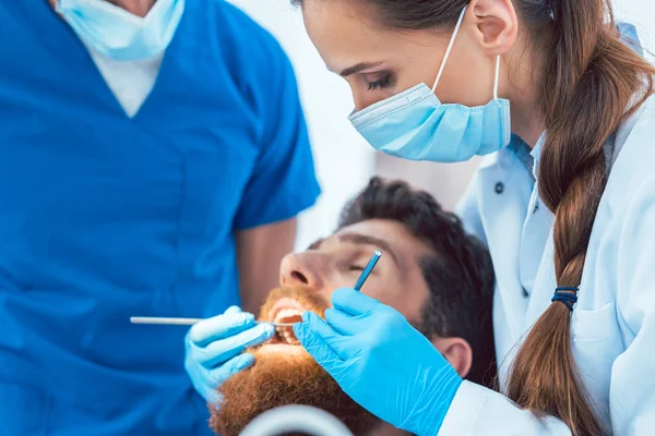 Niezawodne dentysta za pomocą sterylnych narzędzi podczas czyszczenia zębów — Zdjęcie stockowe