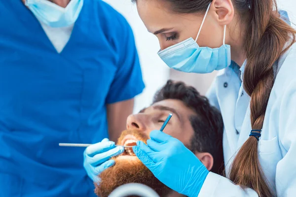 Odontólogo confiable usando instrumentos estériles mientras limpia los dientes —  Fotos de Stock