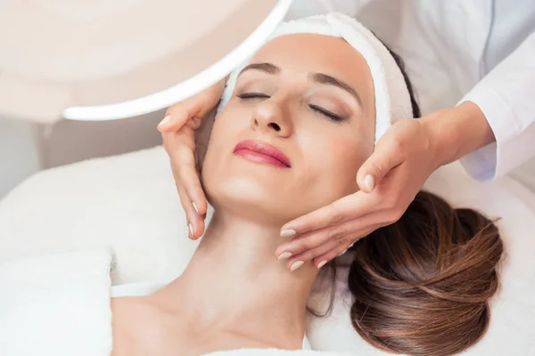Mujer relajada sonriendo bajo los beneficios del masaje facial antienvejecimiento —  Fotos de Stock