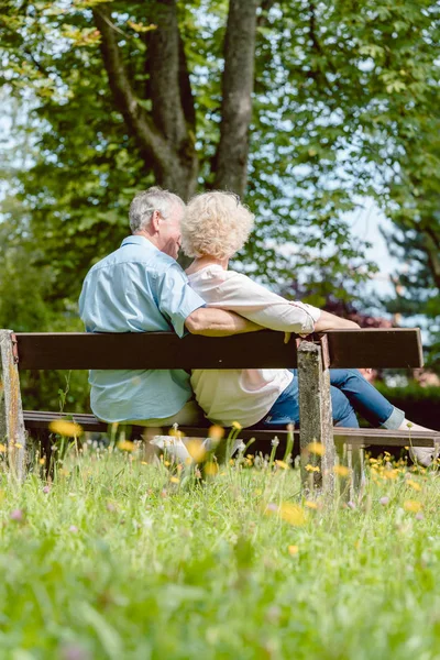 Pareja de ancianos románticos sentados juntos en un banco en un día tranquilo — Foto de Stock