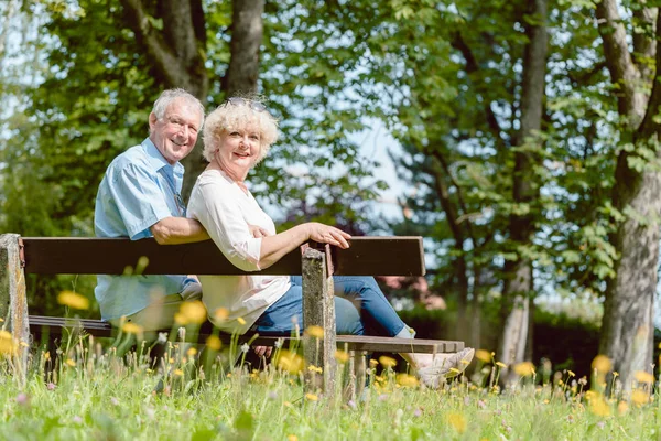 Романтическая пожилая пара, сидящая вместе на скамейке в спокойный день — стоковое фото