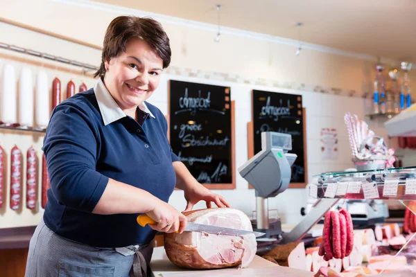 Experienced butcher shop assistant cutting ham — Stock Photo, Image