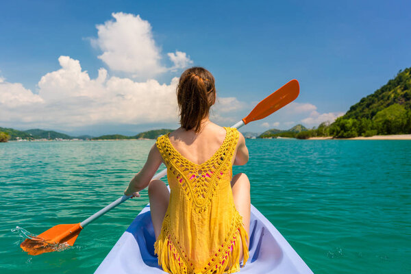 Young woman paddling a canoe during vacation in Flores Island, Indonesia