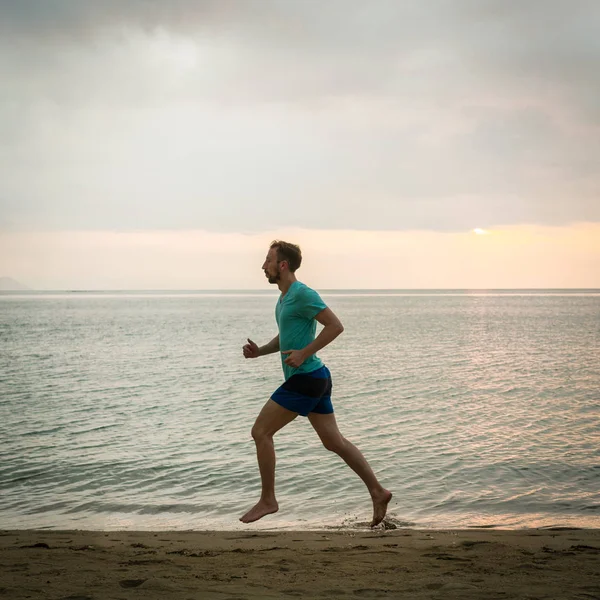 Atlético joven corriendo en la playa durante la sesión de entrenamiento cardiovascular — Foto de Stock
