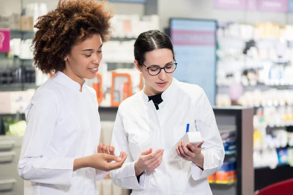 Dwa farmaceutów analizując pakiet nowych farmaceutycznych — Zdjęcie stockowe