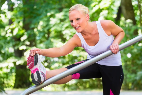 Mladá žena, táhnoucí se před sportem na fitness stezka — Stock fotografie