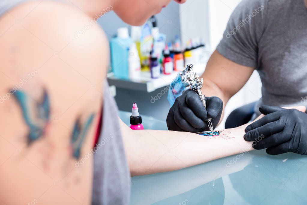 Close-up of the hands of a skilled tattoo artist wearing black gloves