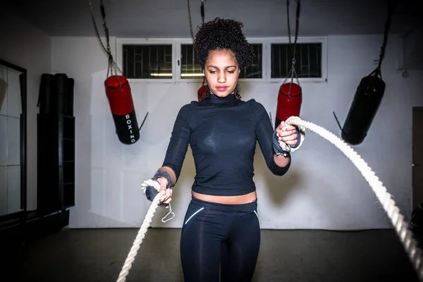 Jovem mulher apta a se exercitar com cordas de batalha durante o treinamento funcional — Fotografia de Stock