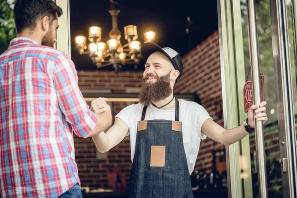 Barbeiro alegre cumprimentando seu cliente masculino — Fotografia de Stock