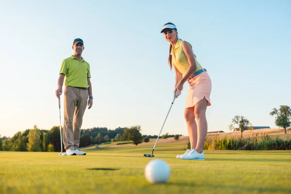 Competitive woman looking at the golf ball with disappointment — Stock Photo, Image