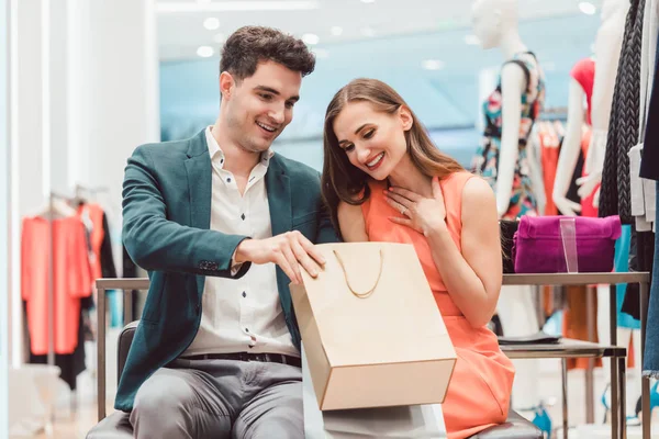 Mulher mostrando a seu homem o que ela comprou na loja de moda — Fotografia de Stock