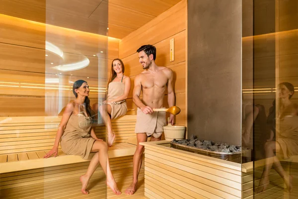 Pessoas jovens e bonitas sorrindo enquanto socializam em uma sauna seca de madeira — Fotografia de Stock