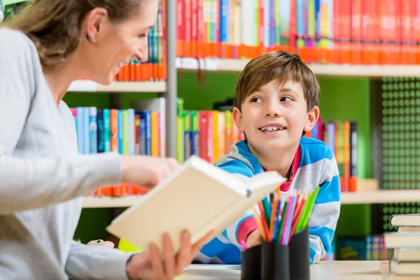 Madre leyendo el libro de la biblioteca a su hijo —  Fotos de Stock