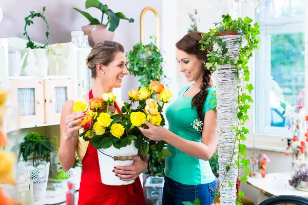 Mujeres en floristería disfrutando de las rosas — Foto de Stock