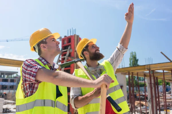 Determinato giovane lavoratore che punta verso l'alto mentre immagina l'altezza di un edificio — Foto Stock