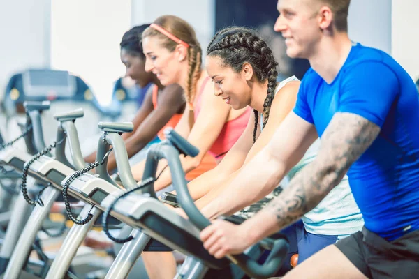 Vista lateral de una hermosa mujer sonriendo mientras pedalea durante la clase de spinning — Foto de Stock