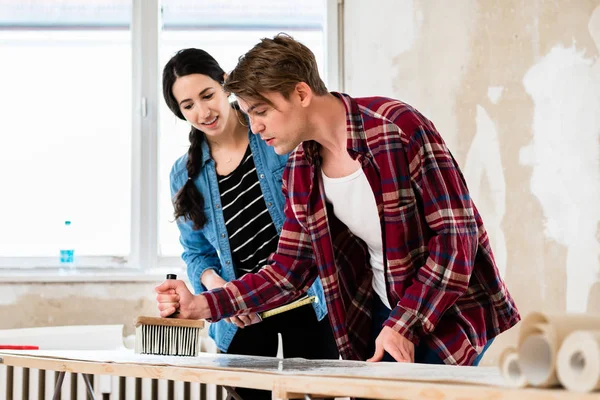 Young couple sharing tools while working on improvement of their new home — Stock Photo, Image