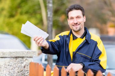 Postman delivering letters to mailbox of a recipient clipart