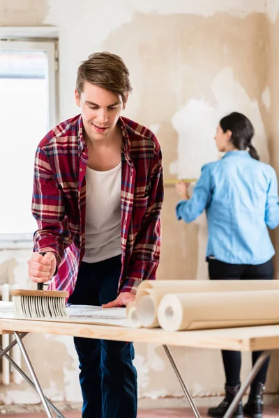 Young Man Applying Adhesive Back Wallpaper Sheet While His Girlfriend — Stock Photo, Image