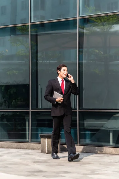 Asiatiska affärsman pratar med mobilen utanför — Stockfoto