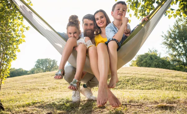 Familieportrett Med Vakker Mor Lekne Barn Som Svinger Hengekøye Mens – stockfoto