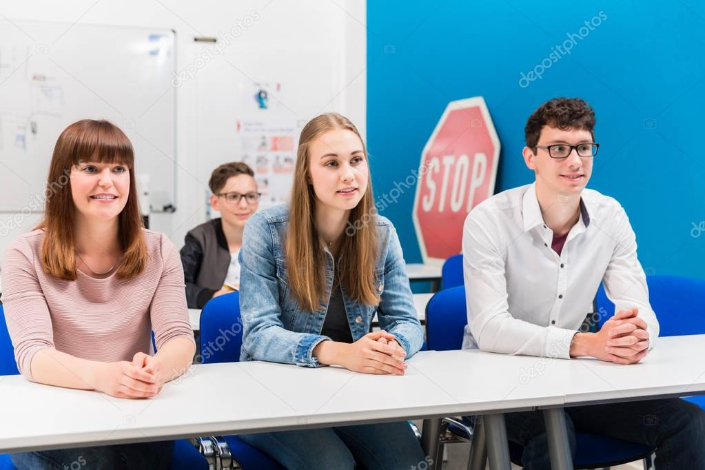 Students in driving lessons listening attentively sitting on benches 