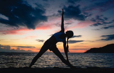 Uygun kadın genişletilmiş üçgen yoga pose rüya gibi bir plajda pratik