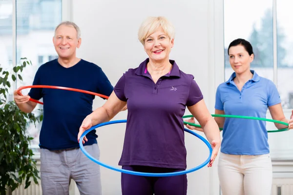 Pareja mayor en fisioterapia haciendo ejercicio con hula hoop —  Fotos de Stock