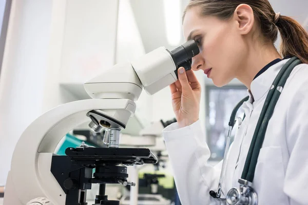 Médico o biólogo examinando el tejido bajo el microscopio — Foto de Stock