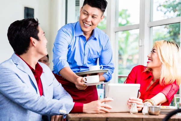 Vänlig asiatiska servitör serverar ett par kaffe — Stockfoto