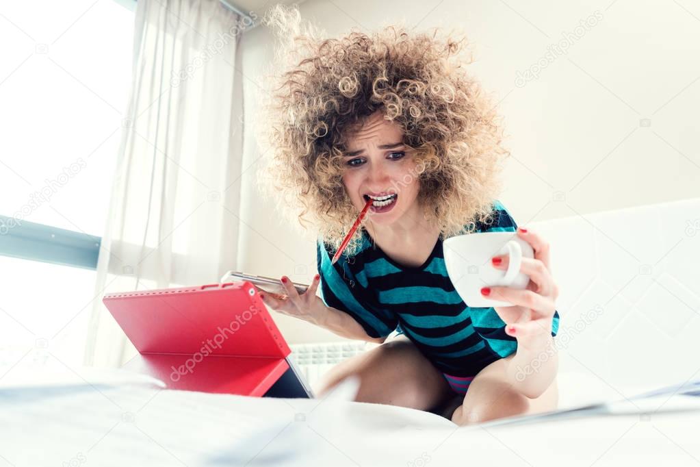 Woman student on her bed learning for exam in panic