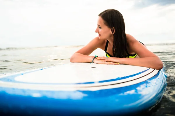 女冲浪手俯卧在冲浪板上向大海冲浪 — 图库照片