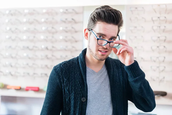 Mannen Framför Hyllan Med Glasögon Optiker Butik Tittar Kameran — Stockfoto