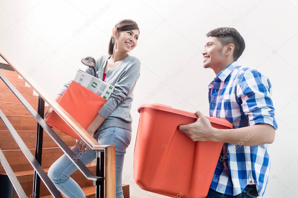 Young indonesian couple, woman and man, in stairway relocating and carrying moving boxes