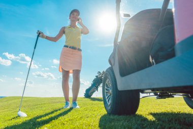 Etkin bir kadın golf sahası üstünde hareket eden telefon üzerinde söz tam uzunlukta