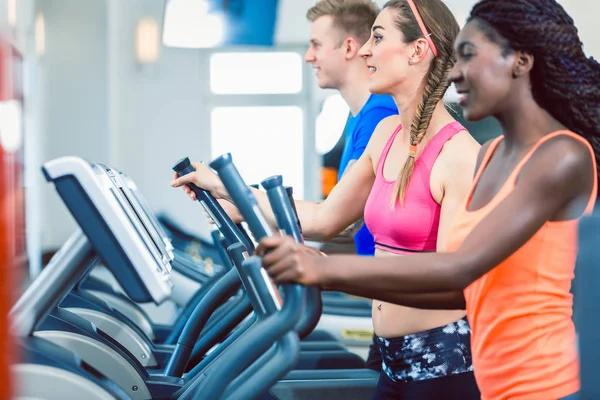 Seitenansicht einer fitten, glücklichen Frau und ihrer Trainingsgruppe auf dem Laufband — Stockfoto