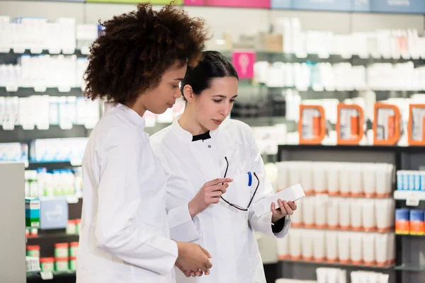 Vue latérale de deux pharmaciens dédiés dans une pharmacie contemporaine — Photo