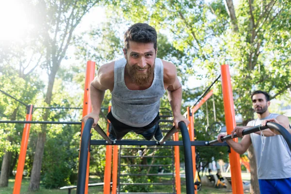 Sportieve jongeman push-ups doen tijdens outdoor training in een fitness park — Stockfoto