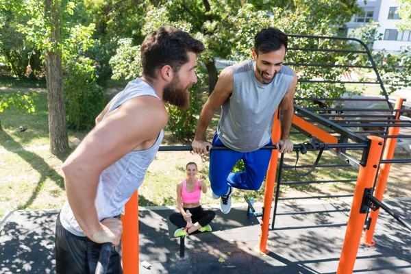 Dos jóvenes musculosos haciendo ejercicios de peso corporal en el parque de fitness —  Fotos de Stock