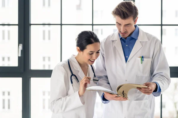 Zwei Ärzte, die gemeinsam die Krankenakte eines Patienten prüfen — Stockfoto