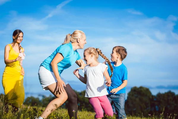 Dos mujeres con niños jugando etiqueta — Foto de Stock