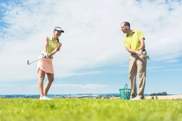 Mujer joven practicando el movimiento correcto durante la clase de golf —  Fotos de Stock