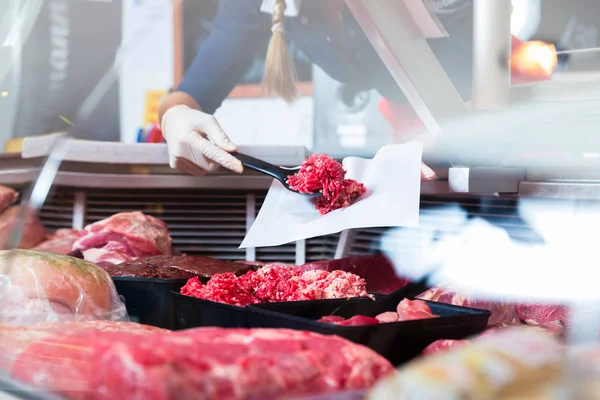 Maso v butcher shop displej do prodeje žena — Stock fotografie