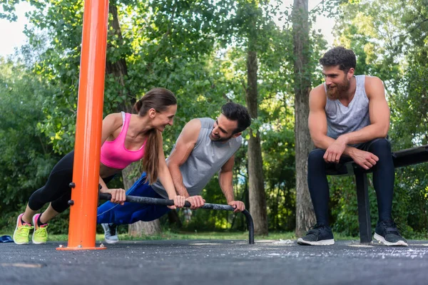 Joven pareja decidida en el amor haciendo flexiones juntos en el parque —  Fotos de Stock