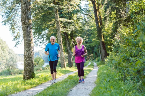 Két aktív nyugdíjas, az egészséges életmód, mosolyogva, miközben joggin — Stock Fotó