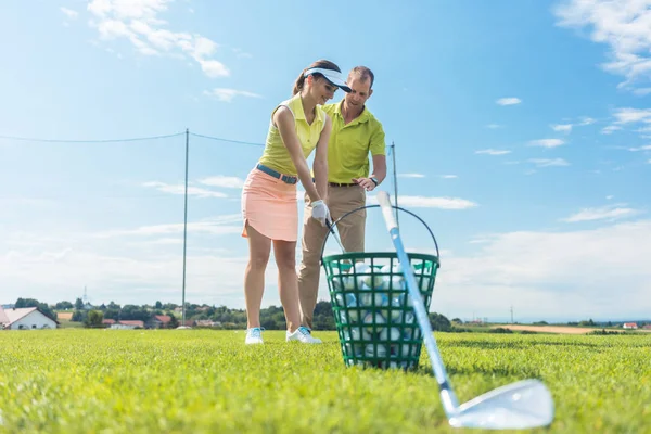 Fröhliche junge Frau lernt den richtigen Griff und die richtige Bewegung für den Golfschläger — Stockfoto
