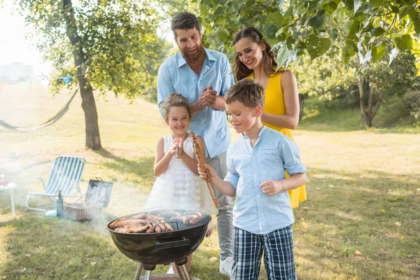 Portrett av lykkelig familie med to barn som står utendørs nær grillfest – stockfoto