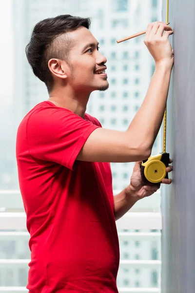 Joven hombre indonesio dimensionamiento con cinta métrica — Foto de Stock