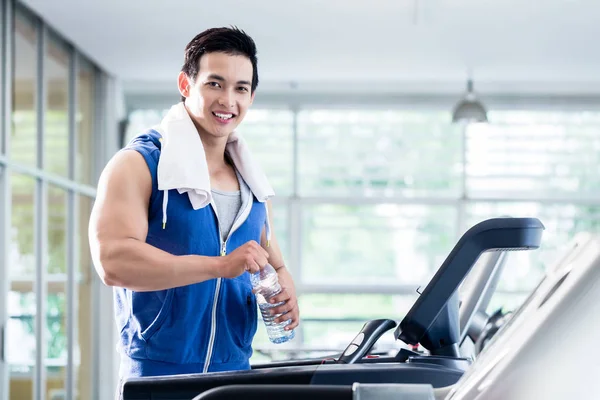 Usmíval se mladý muž na běžecký pás drží láhev s vodou — Stock fotografie